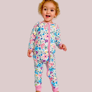 Child wearing a colorful floral onesie on a white background