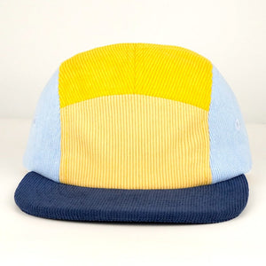 Multicolored cap with yellow, blue, and beige sections on a white background