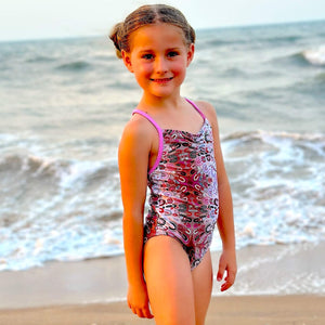 Young girl in a swimsuit standing on a beach with ocean waves in the background