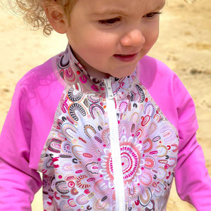 Child wearing a pink and white patterned swimsuit on a beach