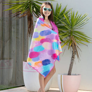 Person holding a colorful towel by a pool with palm trees in the background