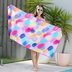 Woman holding a colorful polka dot towel by a poolside