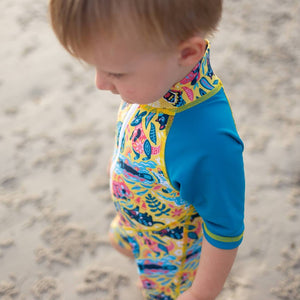 baby-boy-standing-wearing-sun-safe-zip-up-yellow-swimsuit